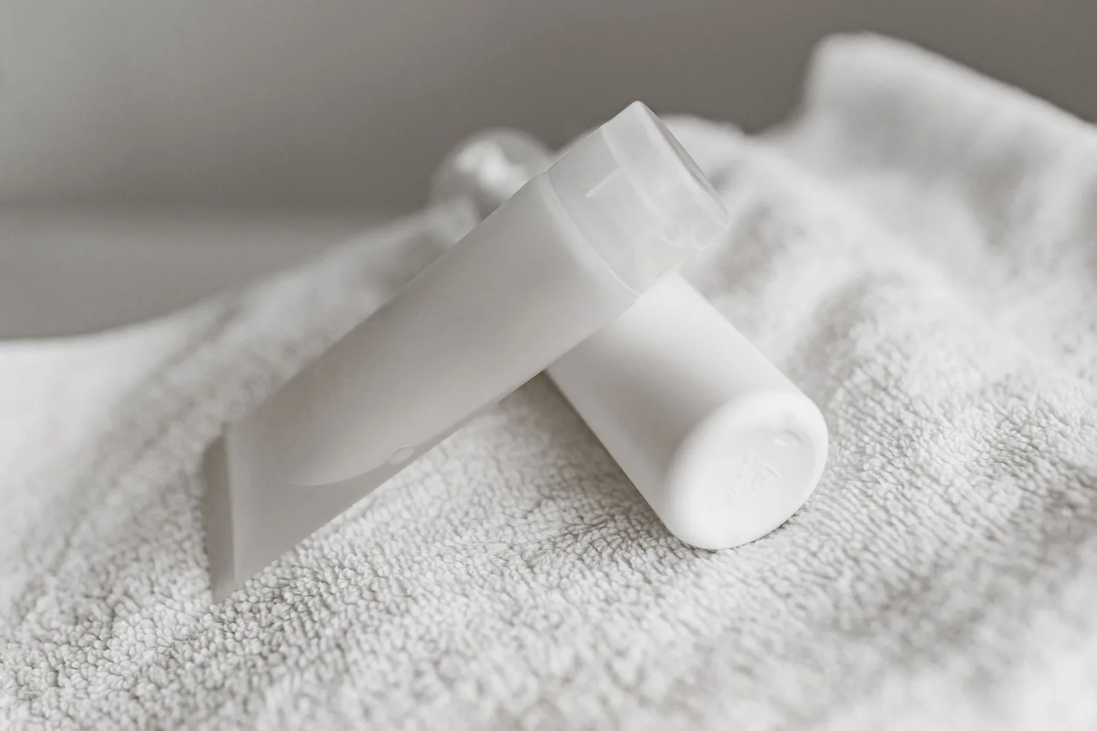 White cosmetic tubes resting on a soft white towel