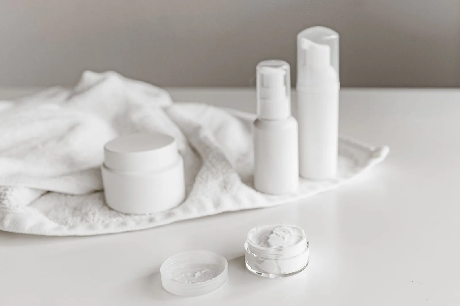 Minimal white skincare products displayed on a pale surface