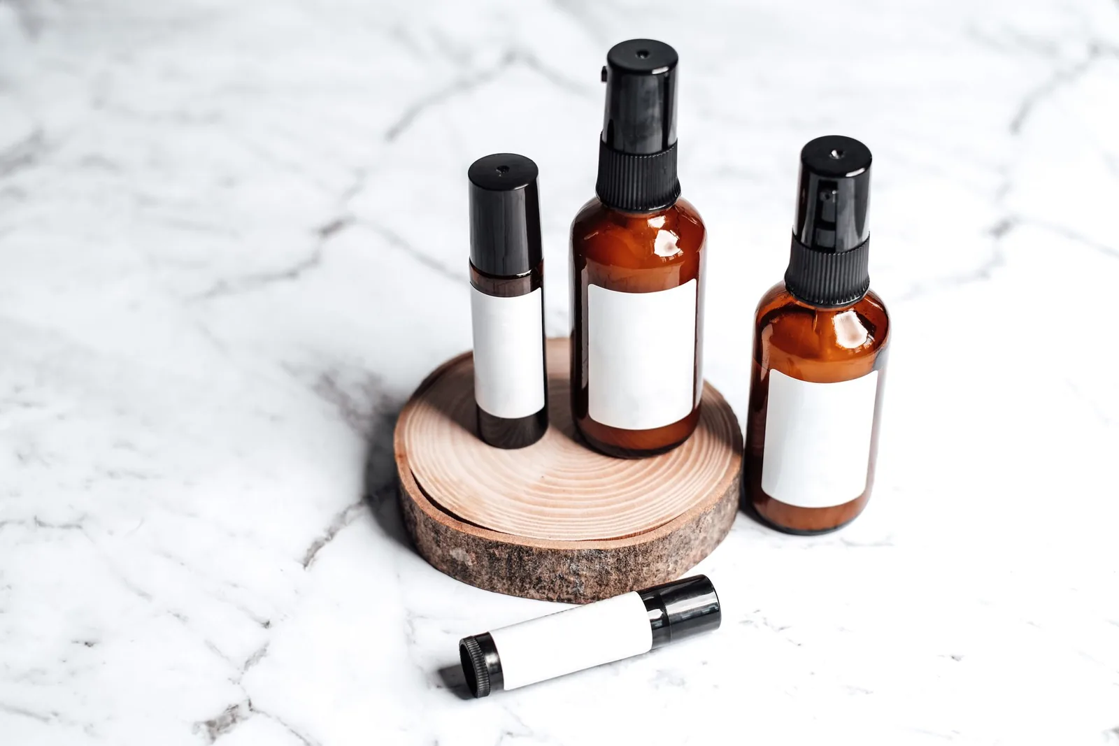 Amber cosmetic bottles with blank labels on a wooden stand