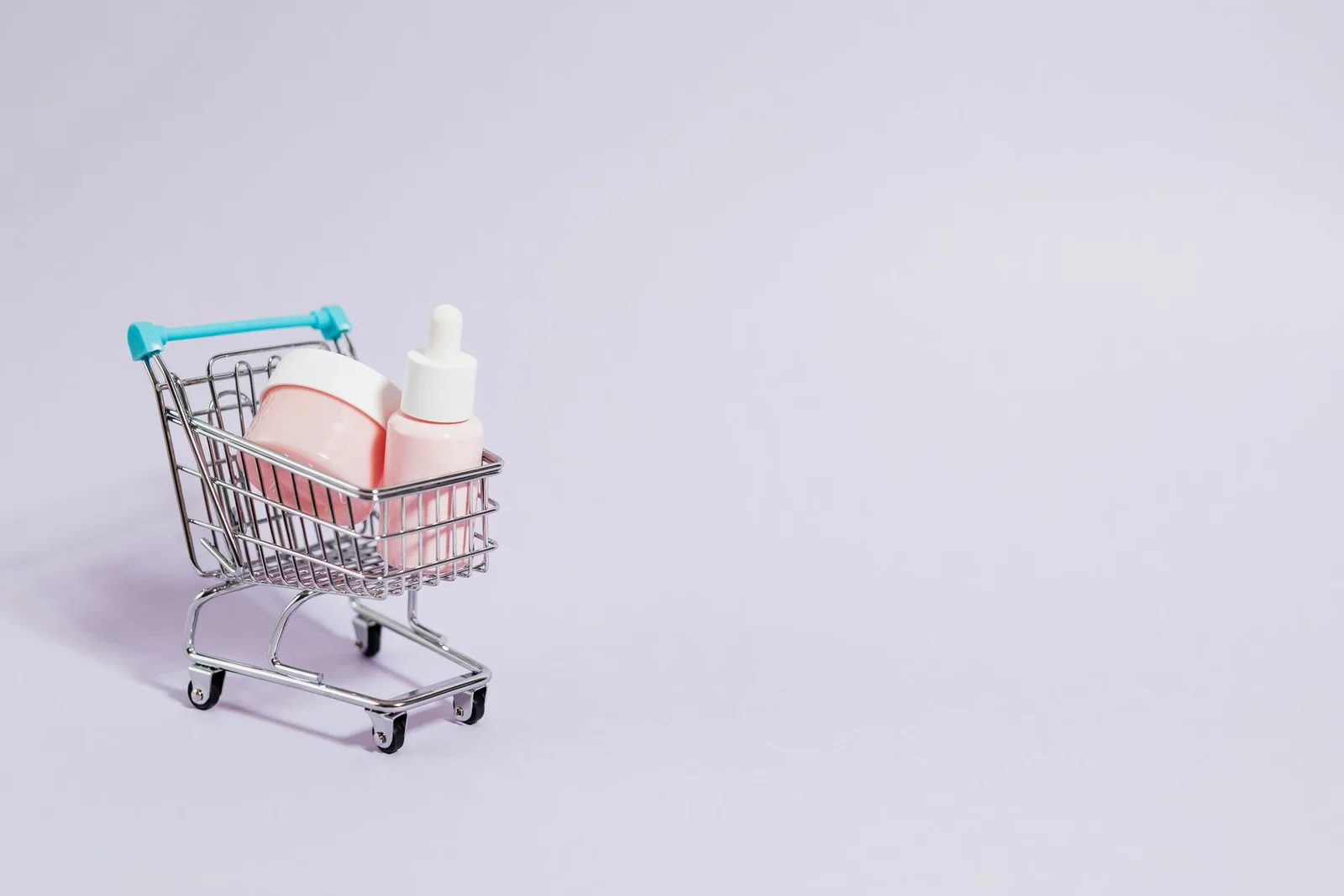 Miniature shopping cart holding a cream jar and dropper bottle